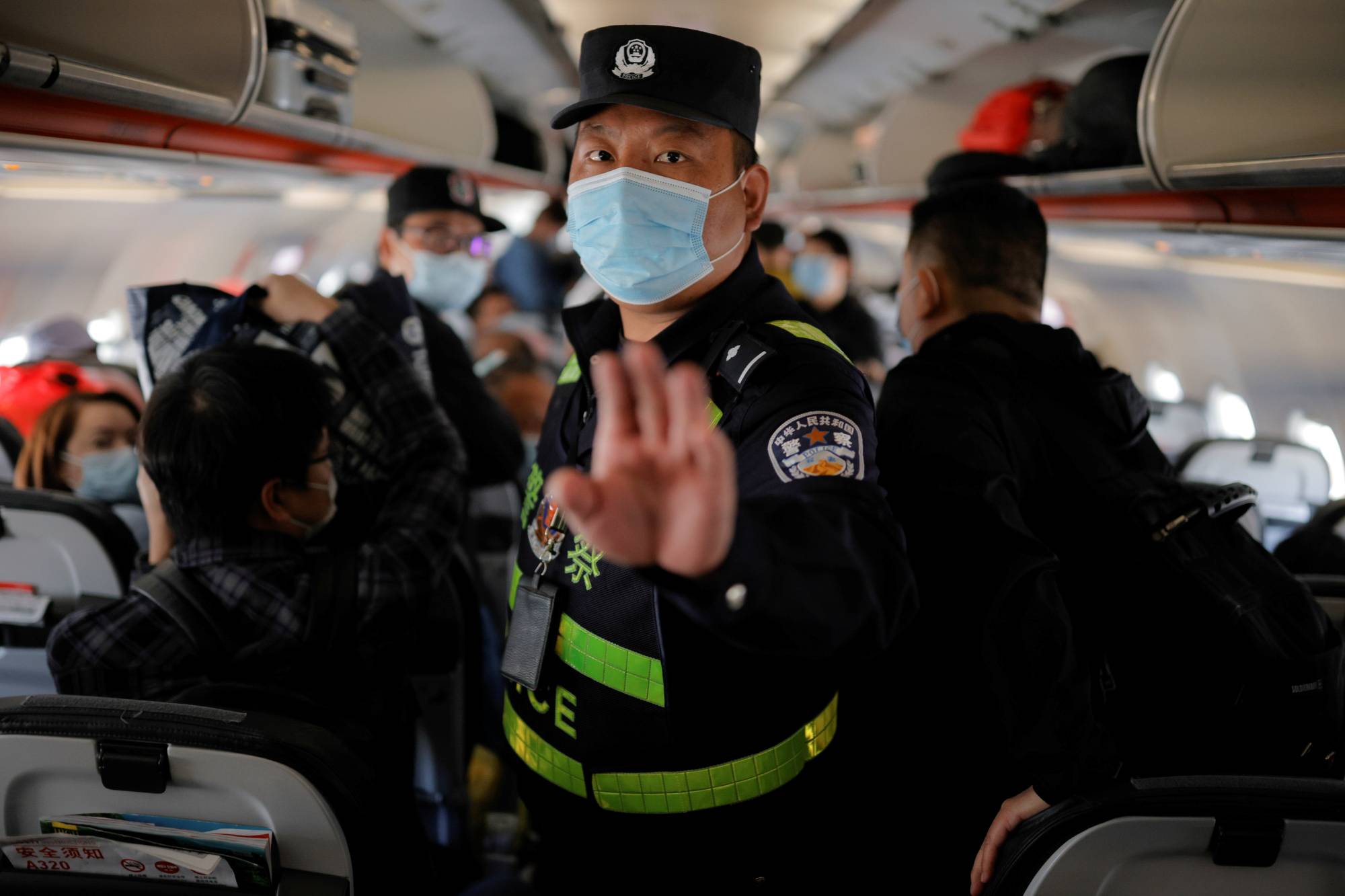 A police officer orders journalists off a plane before all other passengers without explanation while the aircraft is parked on the tarmac at Urumqi airport, Xinjiang Uyghur Autonomous Region, China, on May 5. | REUTERS