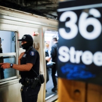 A police officer speaks with an MTA worker as he patrols the 36th Street subway station in New York on Wednesday.  | REUTERS 