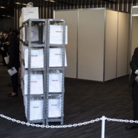 Staff members wait for shareholders to arrive for a general shareholders meeting at the entrance of Toshiba Corp. in Tokyo on March 24. | AFP-JIJI