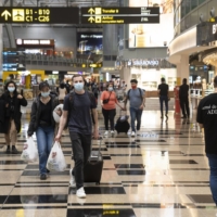 Travelers walk through the transit area at Changi Airport. Singapore was among the first in Asia to start easing travel restrictions by establishing so-called vaccinated travel lanes that ultimately allowed people from 32 countries to visit without quarantine.  | BLOOMBERG