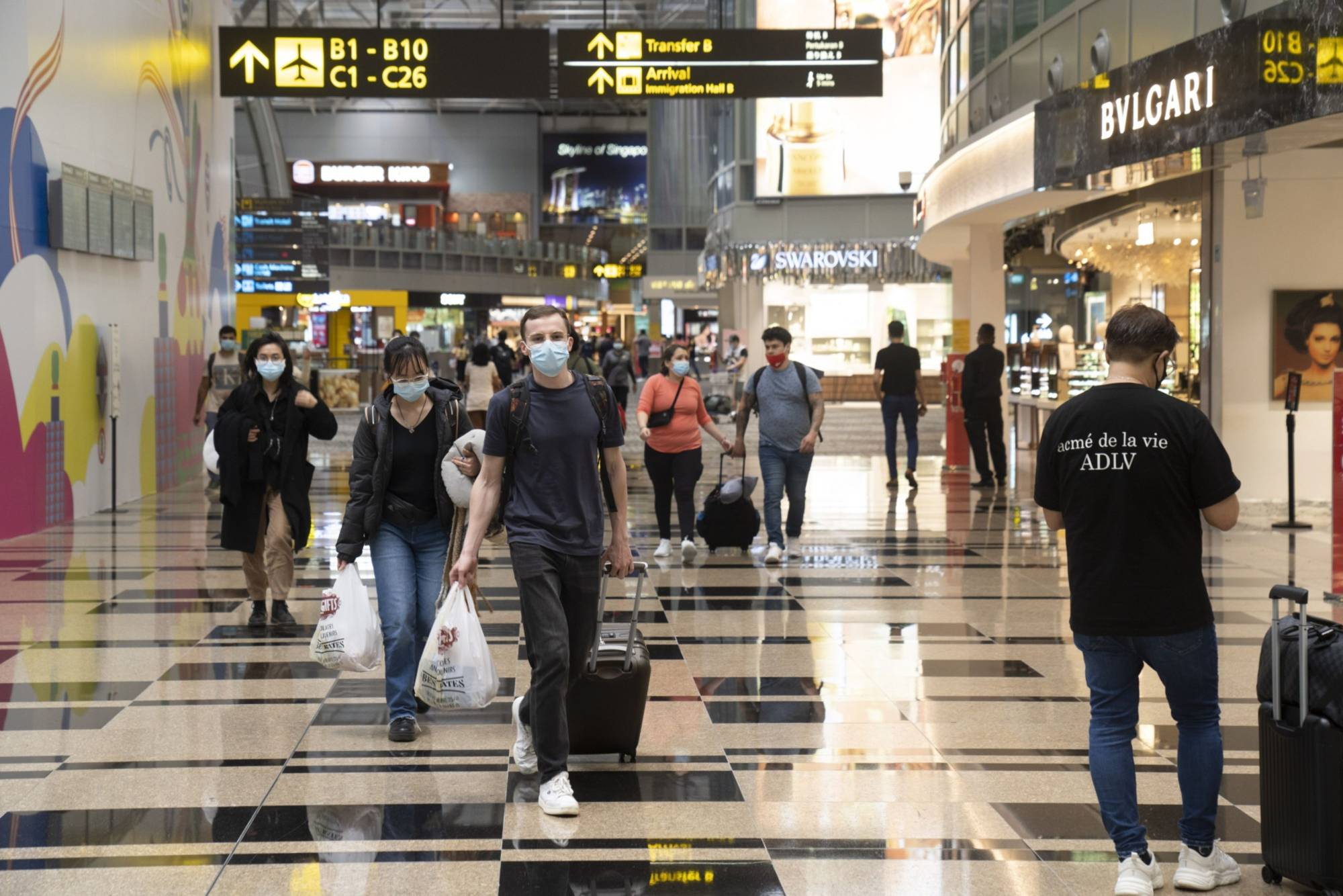Travelers walk through the transit area at Changi Airport. Singapore was among the first in Asia to start easing travel restrictions by establishing so-called vaccinated travel lanes that ultimately allowed people from 32 countries to visit without quarantine. | Bloomberg