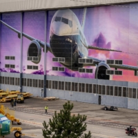 A worker walks under a mural of a Boeing Co. 737-800 airplane outside the company\'s manufacturing facility in Renton, Washington, in March. | BLOOMBERG