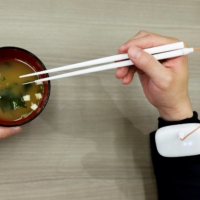 A Kirin Holdings Co. employee demonstrates chopsticks that can enhance the taste of food using an electrical stimulation waveform that was jointly developed by the company and Meiji University\'s School of Science and Technology Professor Homei Miyashita, in Tokyo on Friday. | REUTERS