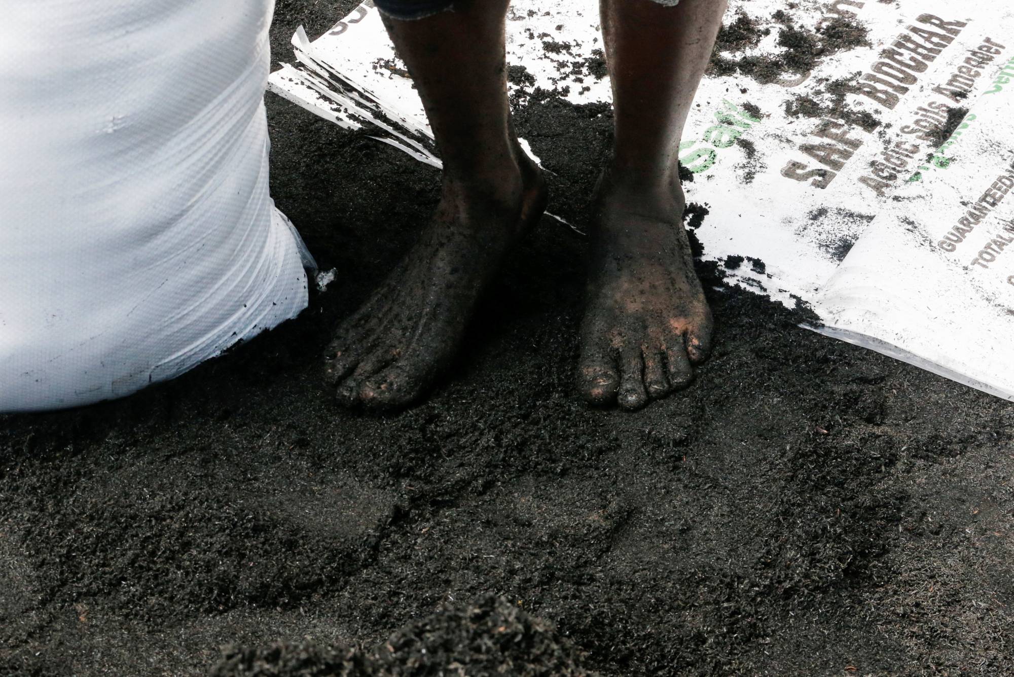A person mixes organic fertilizer made from disposed rice husks and other agricultural chaff in Mwea, Kenya, on April 6. There is a renewed interest in organic fertilizer as global prices for chemical inputs skyrocket due to the war in Ukraine. | REUTERS