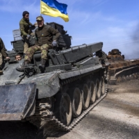 Ukrainians pull an abandoned Russian tank from a field near the village of Lypivka, west of Kyiv, on Friday. | DAVID GUTTENFELDER / THE NEW YORK TIMES