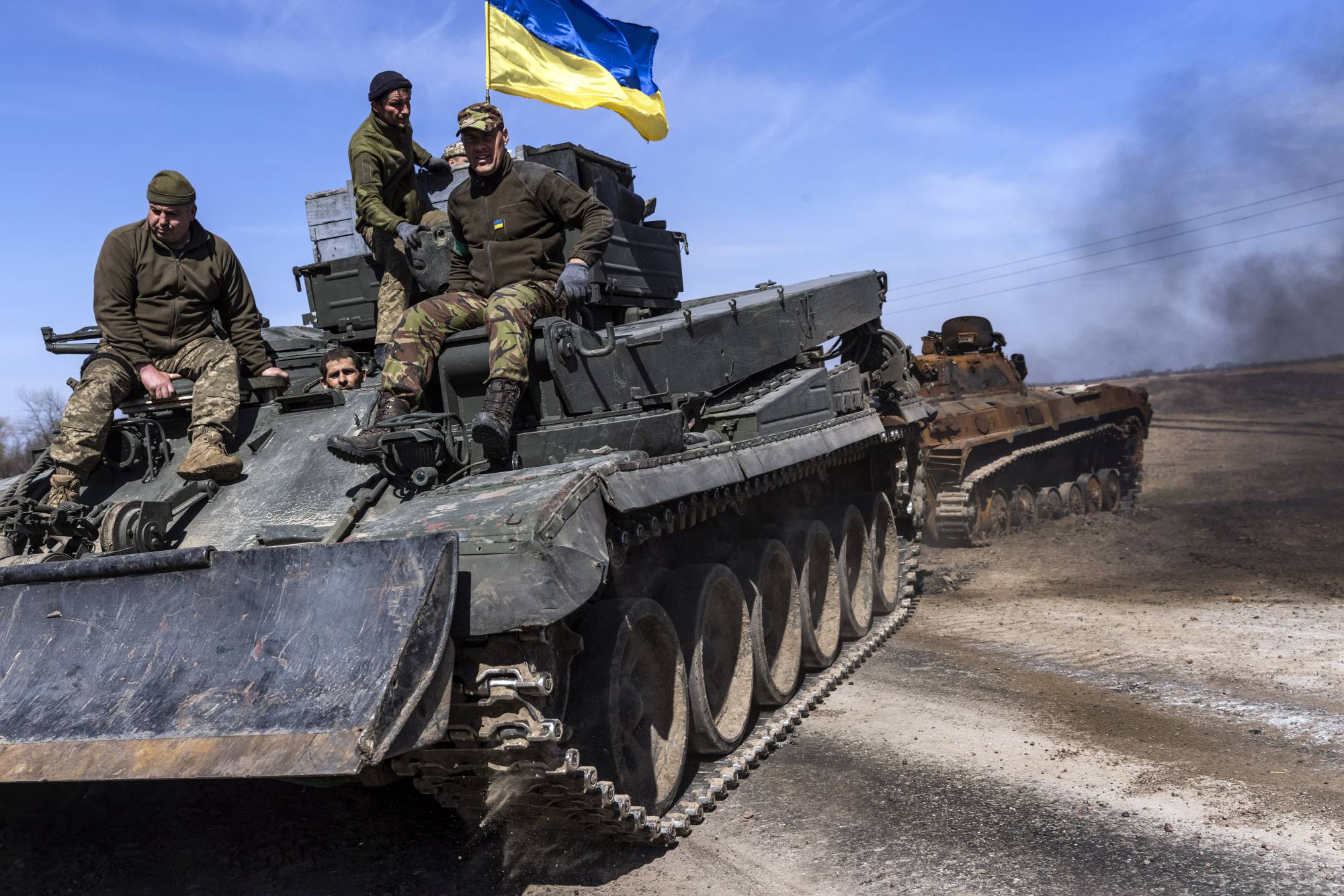 Ukrainians pull an abandoned Russian tank from a field near the village of Lypivka, west of Kyiv, on Friday. | David Guttenfelder / The New York Times