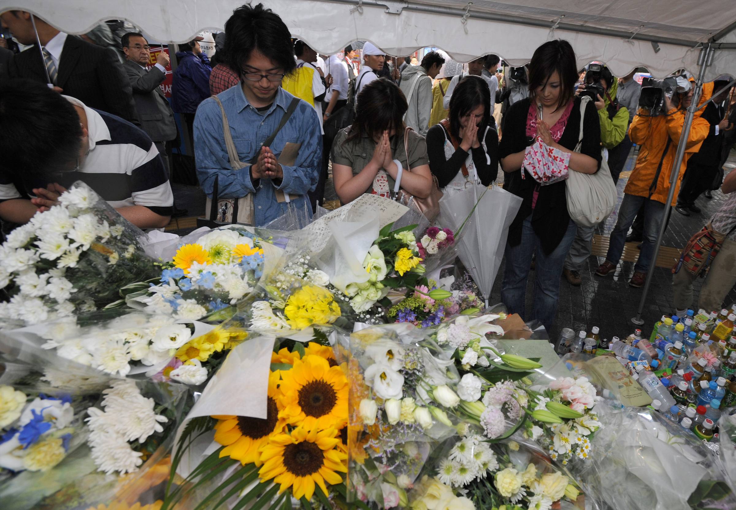 Mourners pray after laying flowers at the site of Tomohiro Kato's stabbing rampage in Tokyo's Akihabara neighborhood in 2008. | ROB GILHOOLY