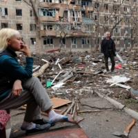 Residents gather in a courtyard near a block of damaged apartment buildings in the southern port city of Mariupol, Ukraine, on Monday. | REUTERS 