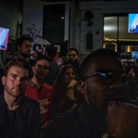 French President Emmanuel Macron is seen on television screens in a bar in Paris as people watch a presidential debate between Macron and Marine Le Pen on Wednesday. | SERGEY PONOMAREV / THE NEW YORK TIMES