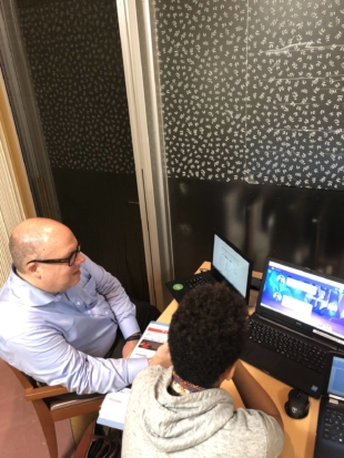 Michael Clemons gives an older child a computer programming lesson. | 