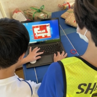 A YouMeWe volunteer helps a young boy develop his computer skills at the Designing Artists Academy.