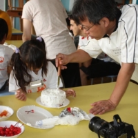 A volunteer helps a young girl decorate a cake at the Designing Artists Academy (DAA) summer camp, which this year runs from Aug. 1 to 5. | BLOOMBERG 