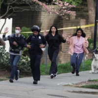 Local residents hold their hands in the air as they run with police while being evacuated to safety at the scene of a reported shooting near Edmund Burke Middle School in the Cleveland Park neighborhood of Washington, D.C., on Friday. | REUTERS