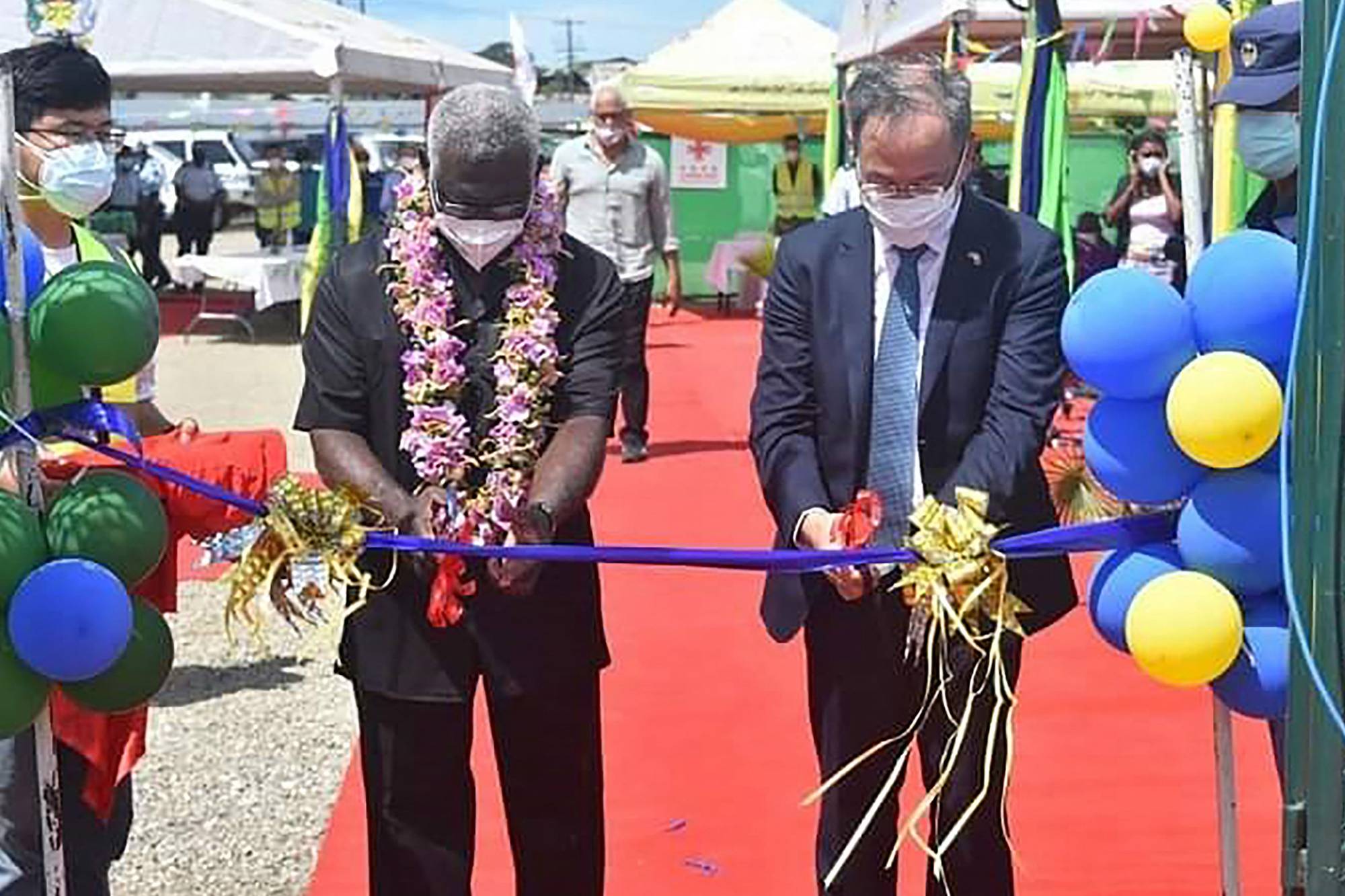 China's Ambassador to the Solomon Islands Li Ming (right), and Solomon Islands Prime Minister Manasseh Sogavare (left) cutting a ribbon during the opening ceremony of a China-funded national stadium complex in Honiara, Solomon Islands. The stadium complex, reportedly worth $53 million, will host the 2023 Pacific Games. | AFP-JIJI