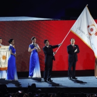 A representative from China waves the Olympic Council of Asia flag after it was handed over by Indonesia during the closing ceremony of the 2018 Asian Games in Jakarta on Sept. 2, 2018. | REUTERS