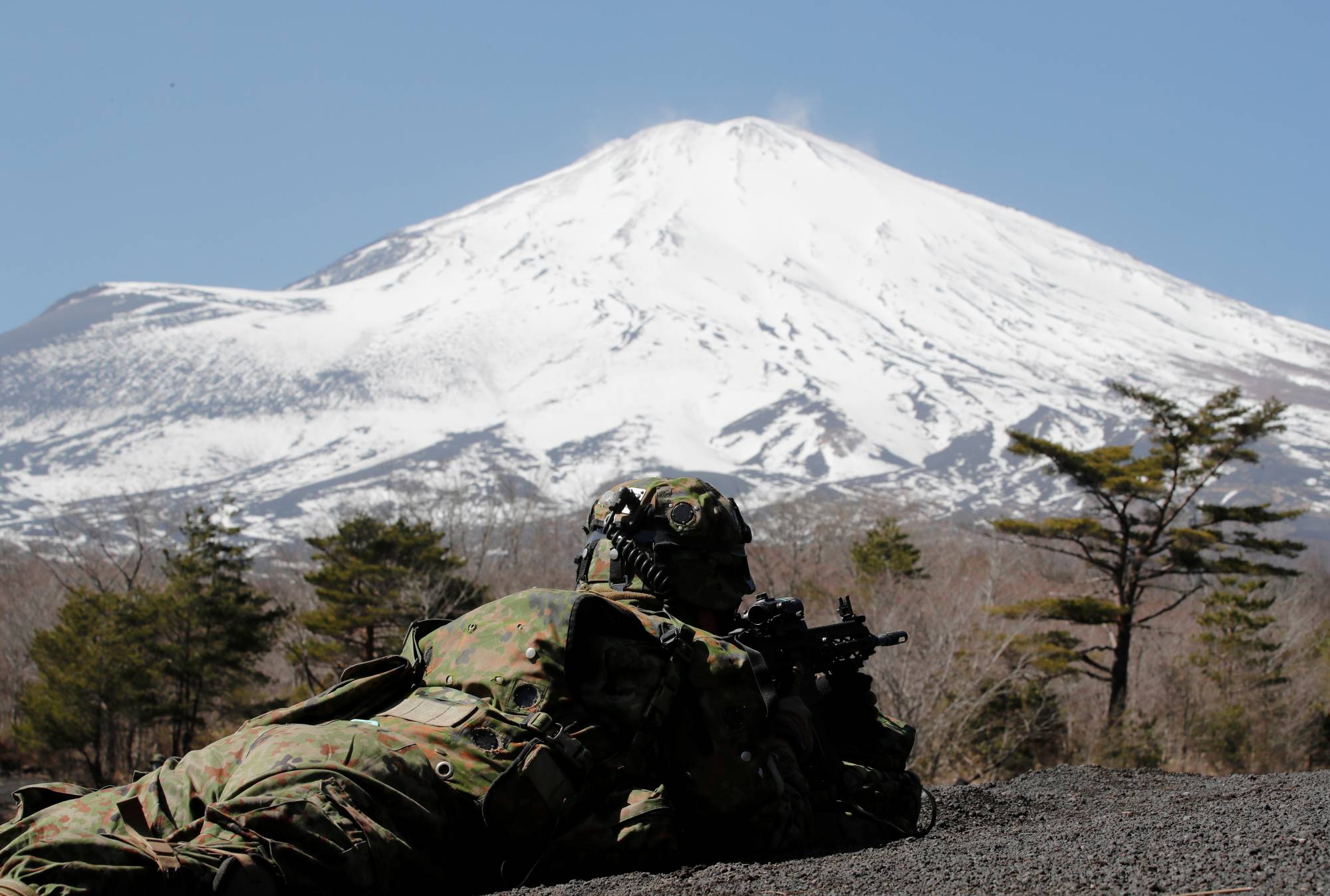 A member of the Self-Defense Force’s Amphibious Rapid Deployment Brigade takes a position as Mount Fuji stands in the background during joint exercises with the U.S. Marine Corps in Gotemba, Shizuoka Prefecture, on March 15. | REUTERS