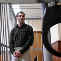 Former U.S. Marine Trevor Reed, charged with attacking police, stands inside a defendants\' cage during a court hearing in Moscow in March 2020. | AFP-JIJI