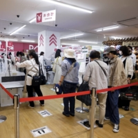 Customers wait in line for self-service checkout kiosks at Daiso Industries Co.\'s global flagship store in the Ginza district of Tokyo on Tuesday. | BLOOMBERG