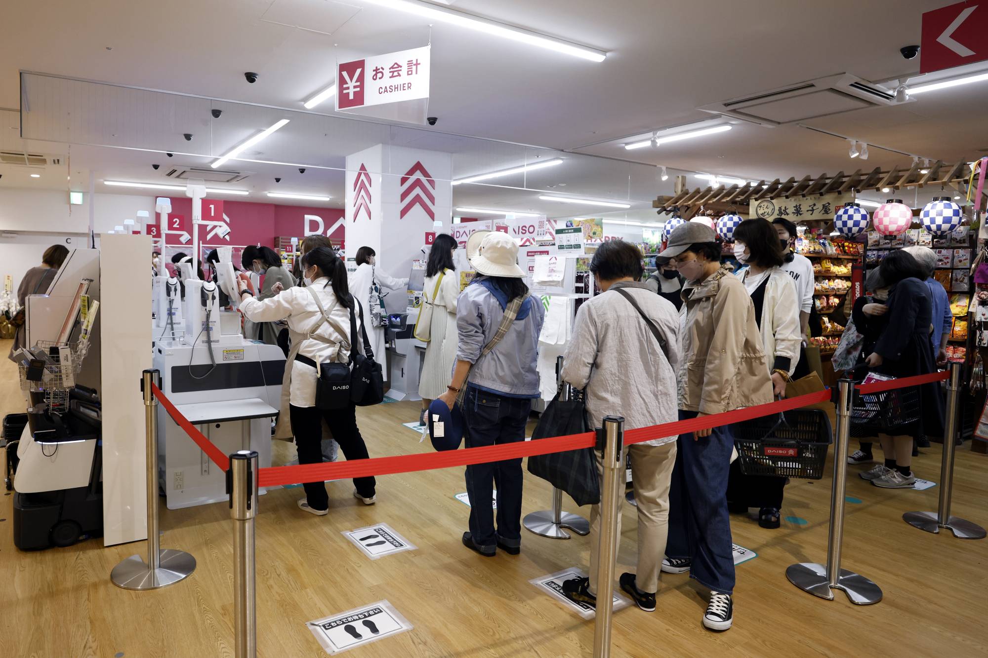 Customers wait in line for self-service checkout kiosks at Daiso Industries Co.'s global flagship store in the Ginza district of Tokyo on Tuesday. | Bloomberg