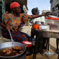 Djeneba Belem prepares to sell bean cakes which she fries in cooking oil made from palm oil, on a street in Abidjan, Ivory coast, on April 10. | REUTERS
