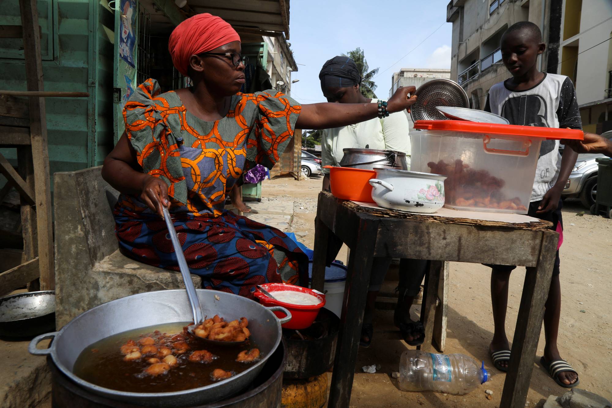 Djeneba Belem prepares to sell bean cakes which she fries in cooking oil made from palm oil, on a street in Abidjan, Ivory coast, on April 10. | REUTERS