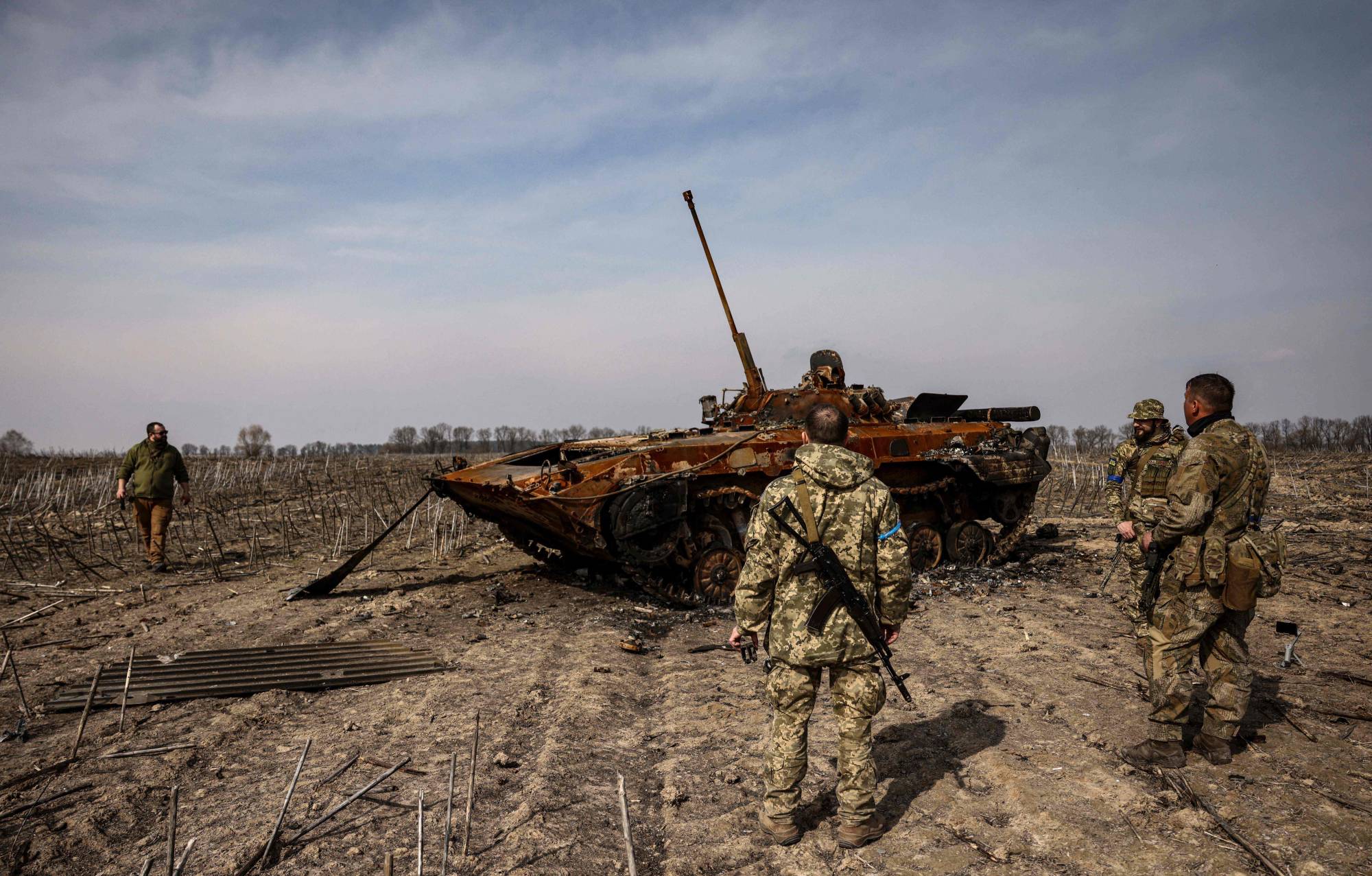 Ukrainian soldiers stand by a burnt Russian tank on the outskirts of Kyiv, on March 31.  | AFP-Jiji