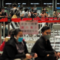 People line up to receive the Medigen and Moderna COVID-19 vaccines at Taipei\'s main train station on Friday. | AFP-JIJI