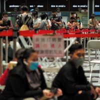 People line up to receive the Medigen and Moderna COVID-19 vaccines at Taipei\'s main train station on Friday. | AFP-JIJI