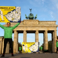 An activist holds a banner reading \"Oil embargo now!\" in front of Berlin\'s Brandenburg Gate in protest of the Russian invasion of Ukraine, on Tuesday. | REUTERS