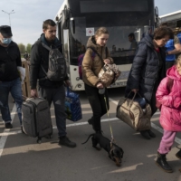 Evacuees from areas around Mariupol arrive with their belongings in Zaporizhzhia, Ukraine, on Tuesday. On a fleet of city buses, flanked by white United Nations and Red Cross vehicles, just over 150 women and children who sheltered for weeks in the belly of Mariupol’s sprawling steelworks arrived at the relative safety of Ukrainian-controlled territory.  | LYNSEY ADDARIO / THE NEW YORK TIMES