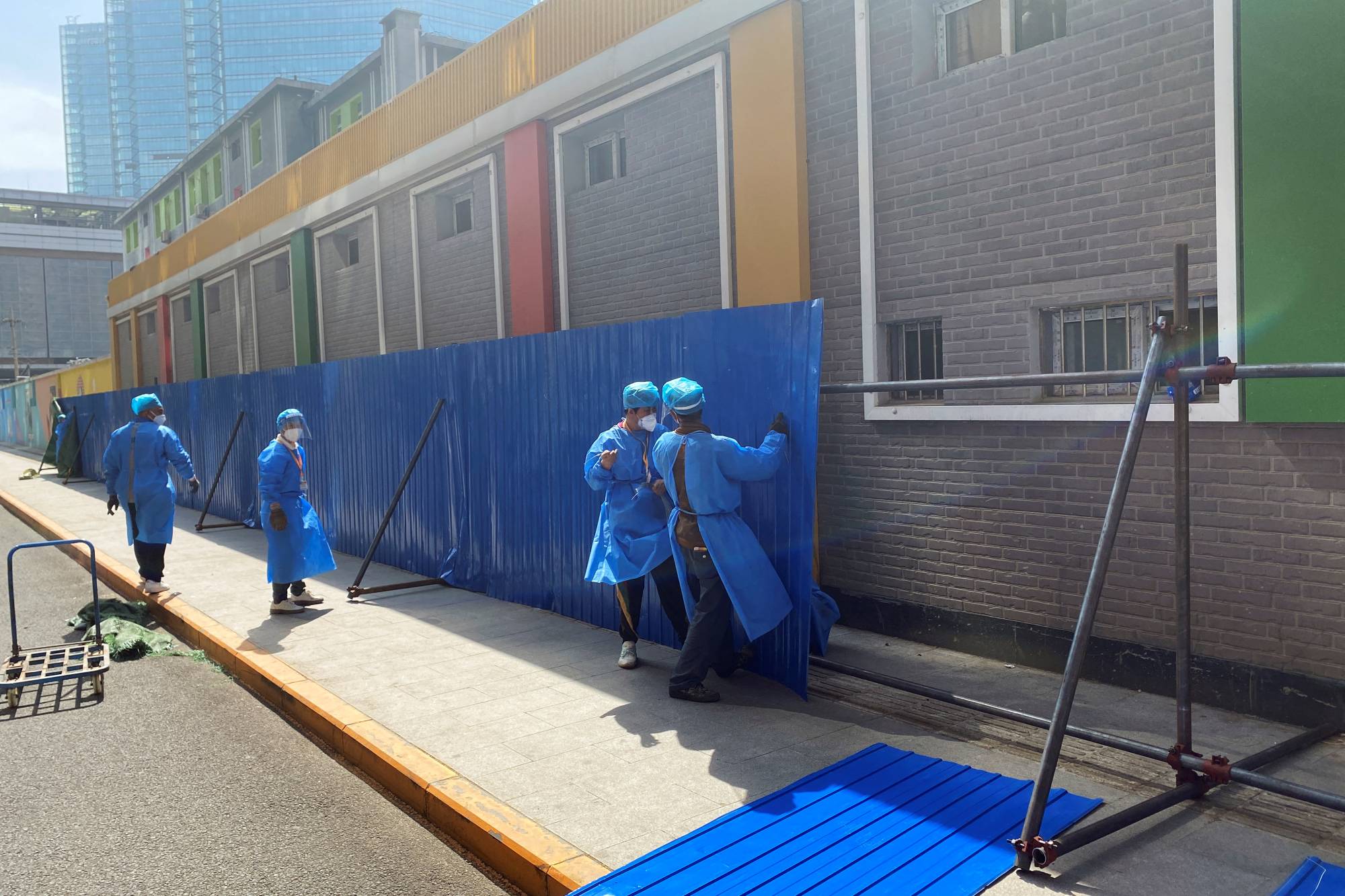 Workers erect barricades outside a residential building under lockdown in the Chaoyang district of Beijing on Wednesday.  | REUTERS 