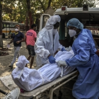 Workers transport the body of a person who died of COVID-19 in New Delhi on April 24, 2021. Nearly a third of excess deaths globally, some 4.7 million, took place in India.  | ATUL LOKE / THE NEW YORK TIMES