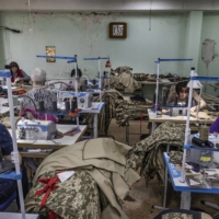 Women sew camouflage uniforms at a garment workshop in Kryvyi Rih on Wednesday. It has shifted to produce military supplies including uniforms, body armor and medical stretchers.  | DAVID GUTTENFELDER / THE NEW YORK TIMES