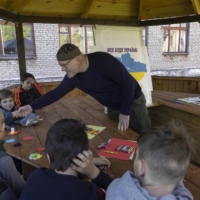 Oleksandr Vilkul greets children at a school that is being used to house evacuees in Kryvyi Rih on Saturday.  | DAVID GUTTENFELDER / THE NEW YORK TIMES