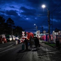 Ukrainian refugees pull their luggage past nongovernmental organization tents as they walk toward the Ukrainian-Romanian border on their way back to Ukraine, at the Siret border crossing in northeastern Romania on April 10. | AFP-JIJI