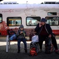 Ukrainian refugees sit on a bench at the train station in Przemysl, Poland, on April 7 as they wait for a train to take them further inside the country. | AFP-JIJI
