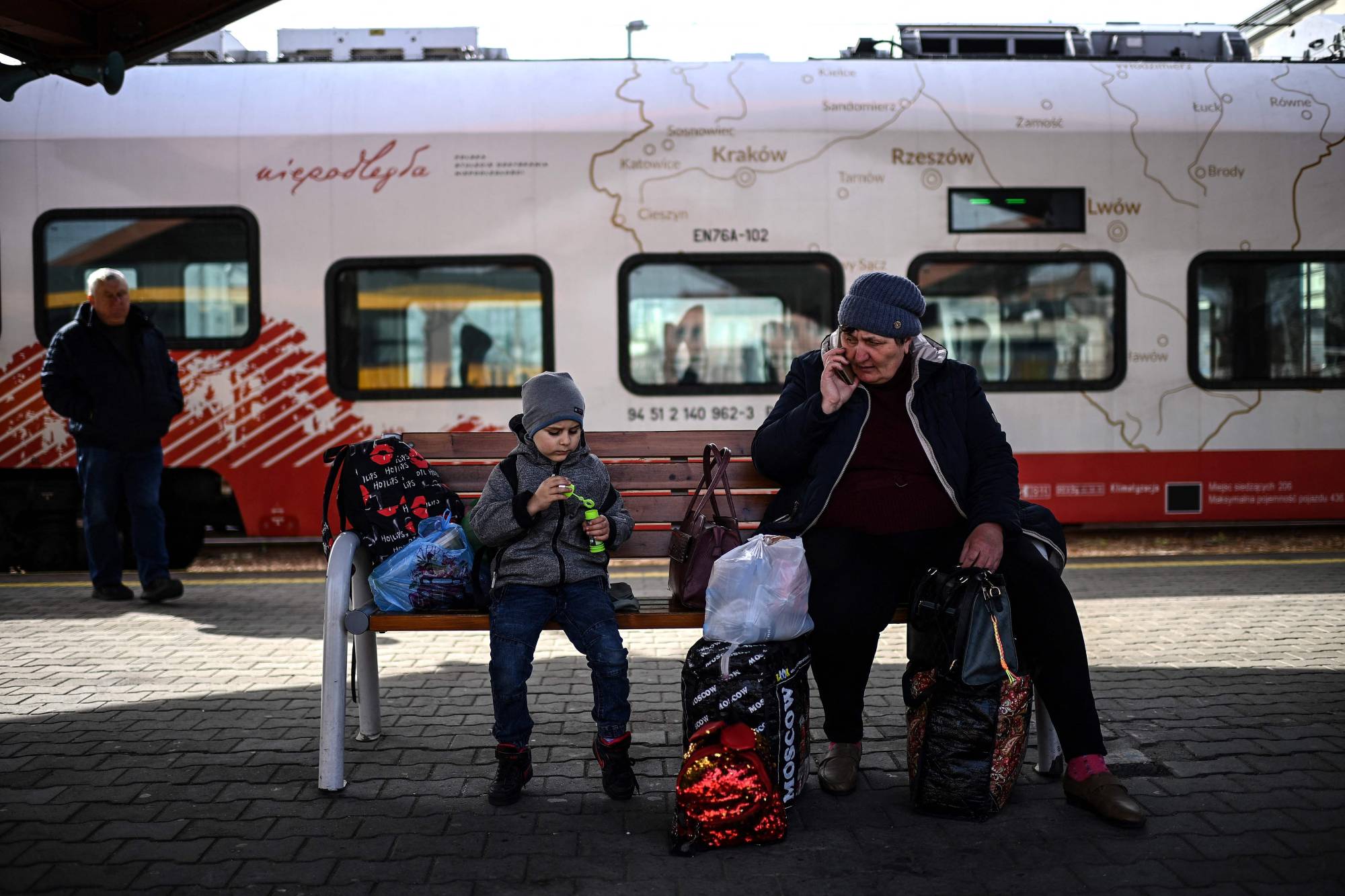 Ukrainian refugees sit on a bench at the train station in Przemysl, Poland, on April 7 as they wait for a train to take them further inside the country. | AFP-JIJI