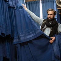 An Afghan vendor displays a burqa at his shop at Mandawi market in Kabul on Sunday. On May 7, the Taliban imposed some of the harshest restrictions on Afghanistan\'s women since they seized power, ordering them to cover up fully in public, ideally with the traditional burqa. | AFP-JIJI
