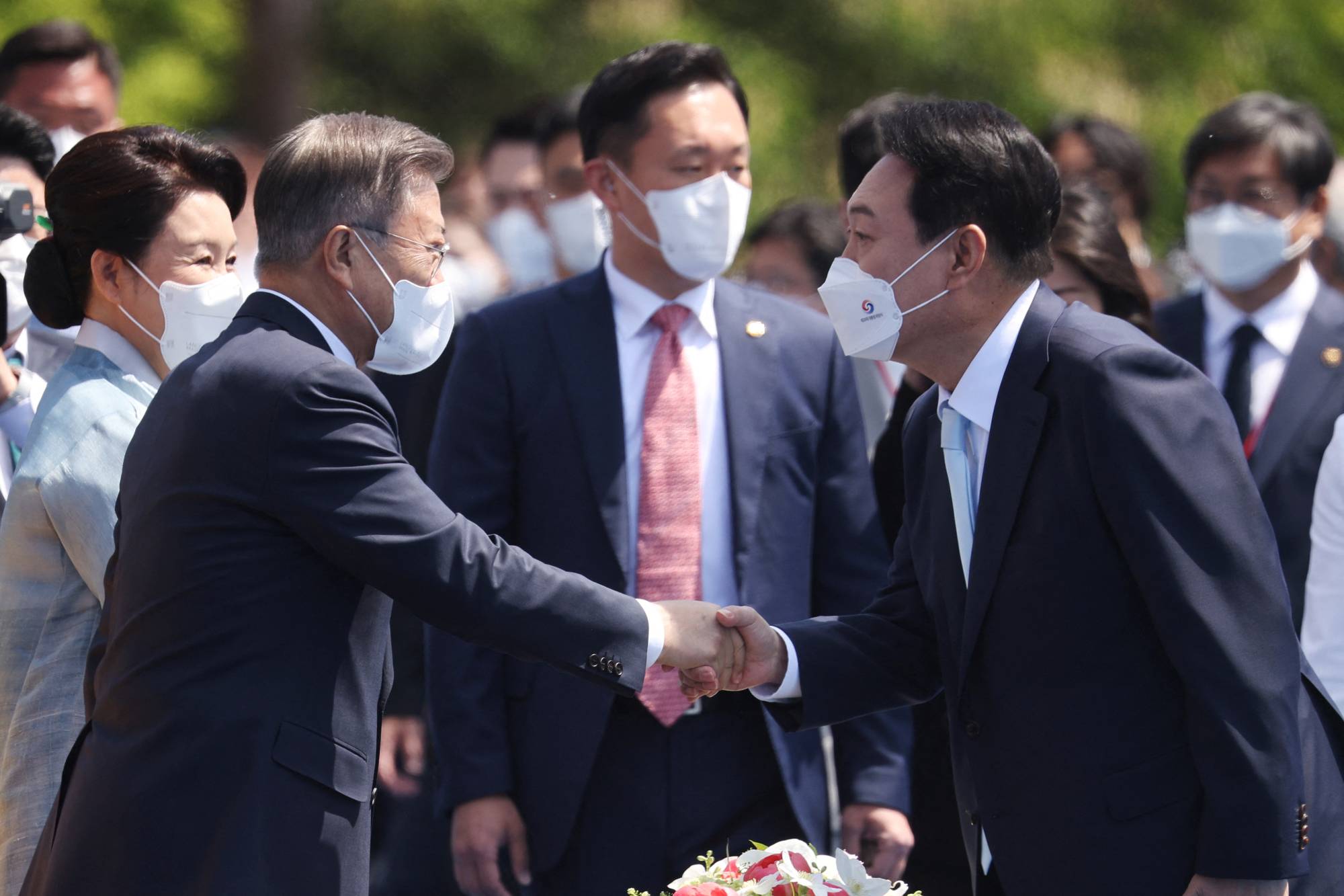 New South Korean President Yoon Suk-yeol shakes hands with former President Moon Jae-in upon his arrival at Yoon's inauguration ceremony at the National Assembly in Seoul on Tuesday. | Pool / VIA REUTERS