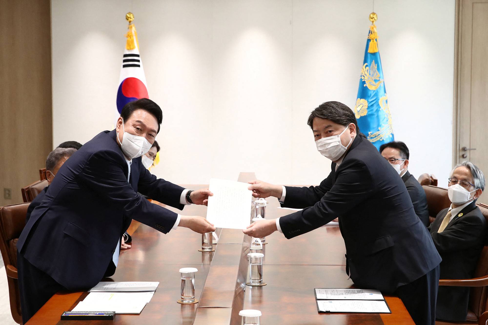 Japanese Foreign Minister Yoshimasa Hayashi (right) delivers a personal letter from Prime Minister Fumio Kishida to new South Korean President Yoon Suk-yeol during a meeting in Seoul on Tuesday. | Pool / via REUTERS