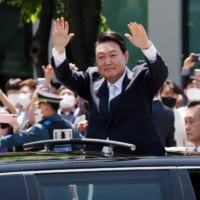 New South Korean President Yoon Suk-yeol waves to supporters as he departs from his inauguration ceremony at the National Assembly in Seoul on Tuesday. | YONHAP / VIA REUTERS   