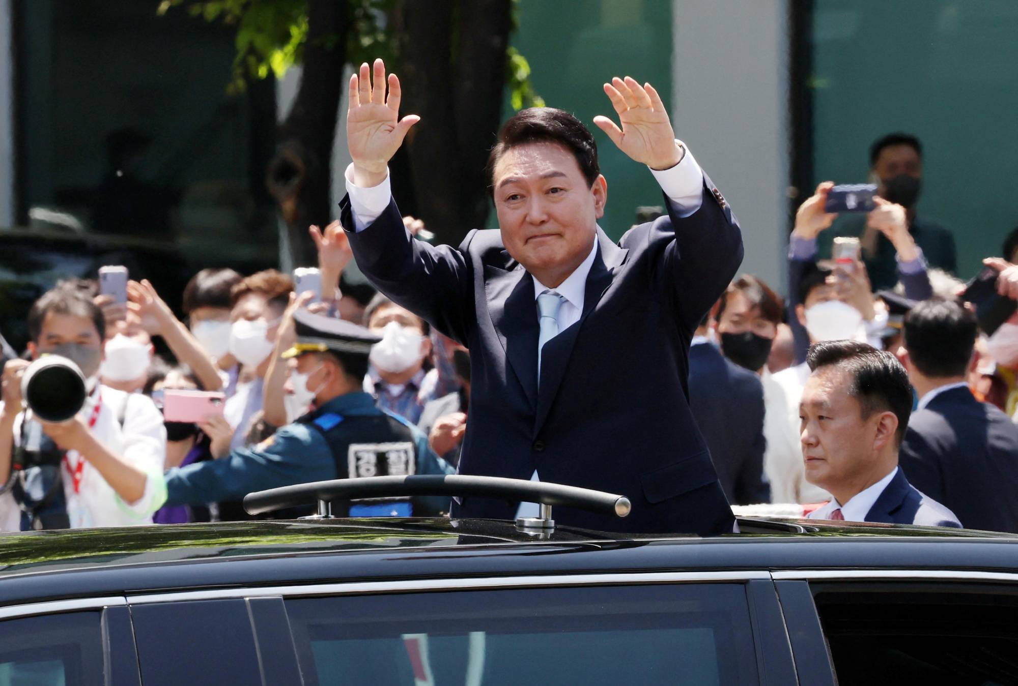 New South Korean President Yoon Suk-yeol waves to supporters as he departs from his inauguration ceremony at the National Assembly in Seoul on Tuesday. | Yonhap / via REUTERS 