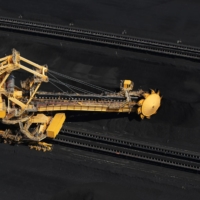A stacker-reclaimer operates next to stockpiles of coal at the Newcastle Coal Terminal in Newcastle, Australia, in 2015. | BLOOMBERG