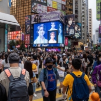 Pedestrians cross the street in the Causeway Bay shopping area of Hong Kong on April 30. | BLOOMBERG

