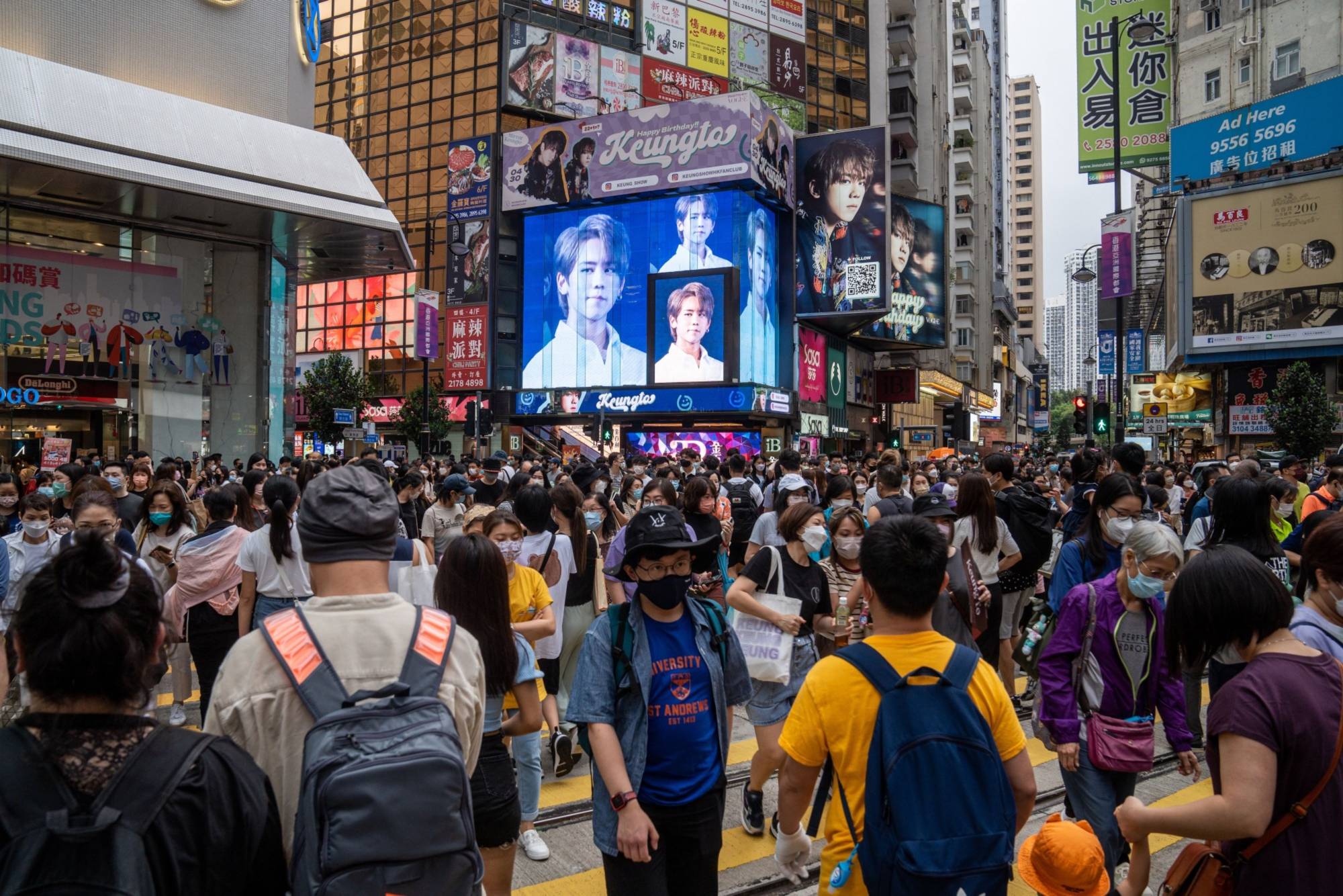 Pedestrians cross the street in the Causeway Bay shopping area of Hong Kong on April 30. | Bloomberg 