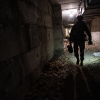 A soldier of the Ukrainian Army’s Carpathian Sich Battalion walks through an underground base in the Kharkiv region of Ukraine on Wednesday. The volunteer unit is deployed along a line of villages and trenched farmland in the Kharkiv region, tasked with holding back Russian forces pushing down from their stronghold in the occupied Ukrainian city of Izium.  | LYNSEY ADDARIO/THE NEW YORK TIMES