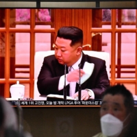 People sit near a screen showing a news broadcast of North Korean leader Kim Jong Un, at the main railway station in Seoul on Thursday. | AFP-JIJI