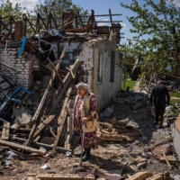 A couple brings their luggage out of their destroyed house on Saturday in the Ukrainian village of Vilkhivka, near the eastern city of Kharkiv. | AFP-JIJI