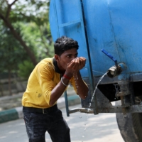 A worker drinks water from a tanker at a construction site in Noida on Thursday.  | REUTERS 