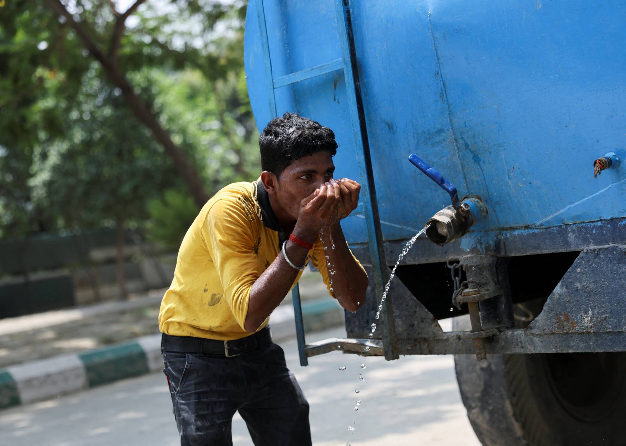 A worker drinks water from a tanker at a construction site in Noida on Thursday. | Reuters 